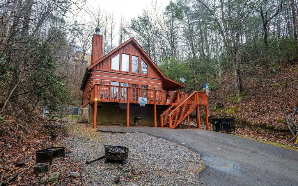 a large wooden house with a staircase in the woods at Highland Hideaway in Gatlinburg