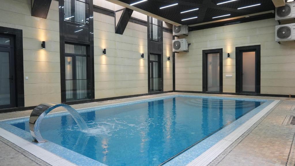 a swimming pool with a water fountain in a building at Avant Express Hotel Pool&Spa in Tashkent