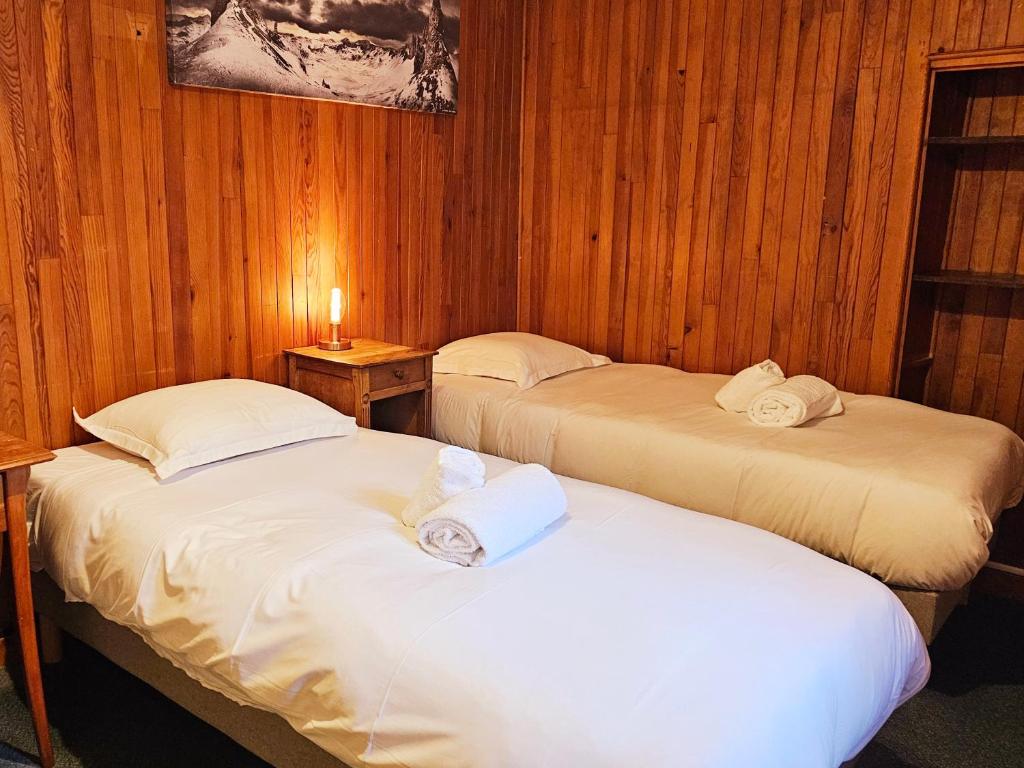 two twin beds in a room with wooden walls at Hôtel Restaurant "La Petite Auberge" in Bourg-Saint-Maurice