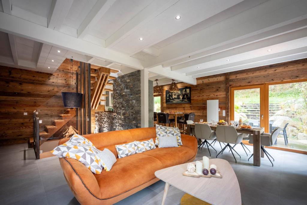 un salon avec un canapé et une salle à manger dans l'établissement Chalet Mökki, bain nordique, balnéo et sauna, à Xonrupt-Longemer