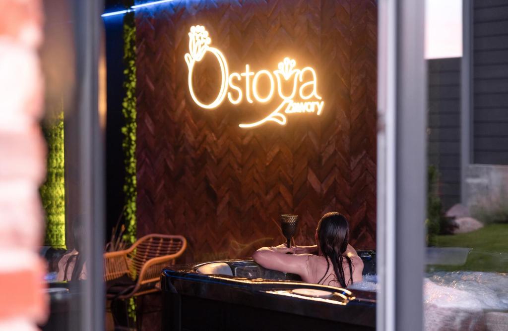 a woman sitting in a bath tub with a glass of wine at Ostoya Zawory -domki premium ,strefa relaksu, basen in Zawory