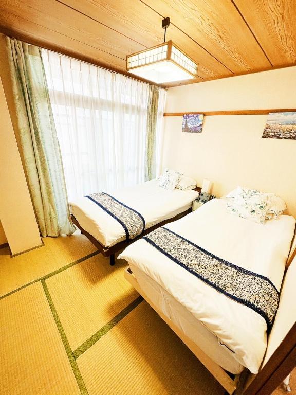 two beds in a room with a window at メゾンドリバージュ205 in Tokyo