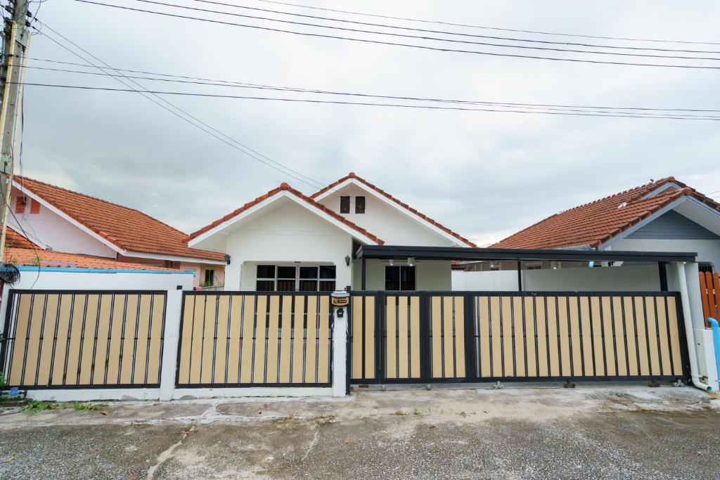ein weißes Haus mit einem Holztor und einigen Häusern in der Unterkunft ME House Banchang in Ban Chang