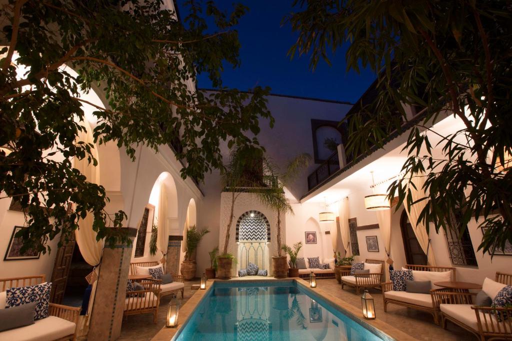 un patio con piscina por la noche en Riad Dar Alfarah, en Marrakech