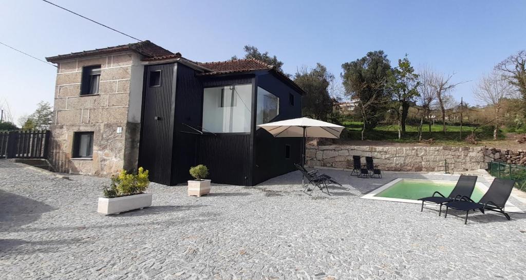 a small house with an umbrella and a swimming pool at Casa da Igreja-Abadim in Cabeceiras de Basto