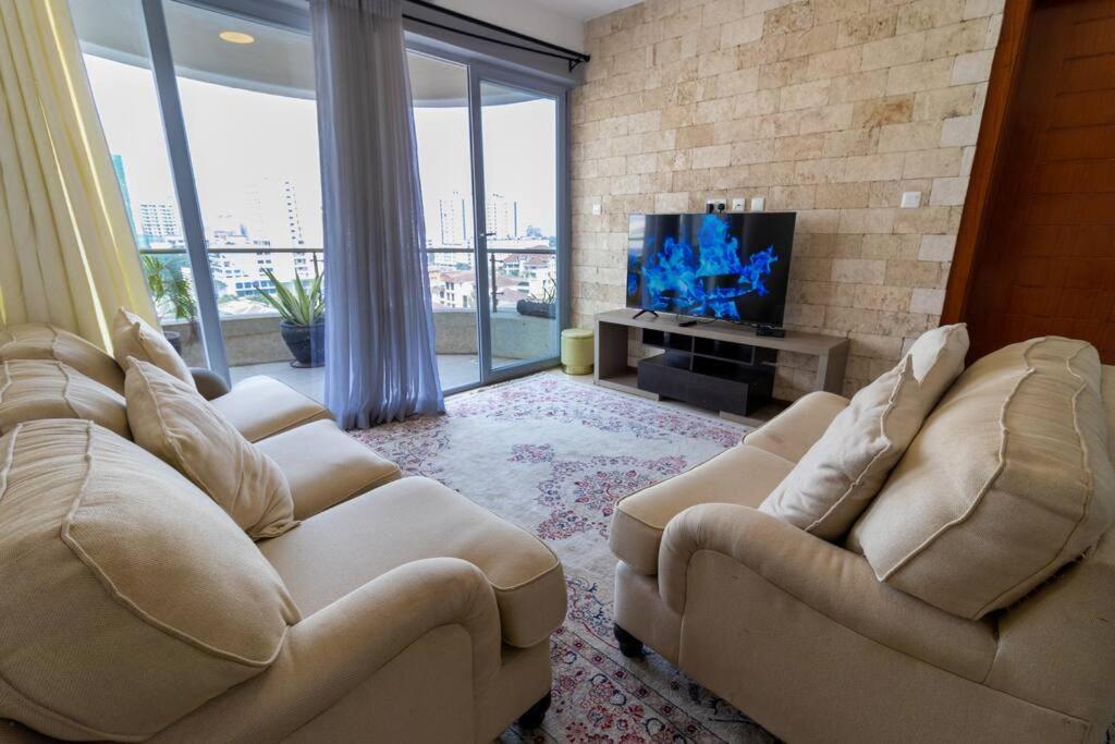 a living room with two couches and a flat screen tv at Elegant 2 BED apt in Kilimani with balcony views in Nairobi