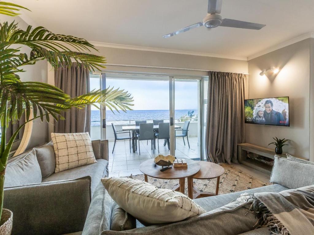 a living room with a couch and a table at Beachfront Apartment Shakas Rock - Martinique, Pool, Ocean Views in Ballito