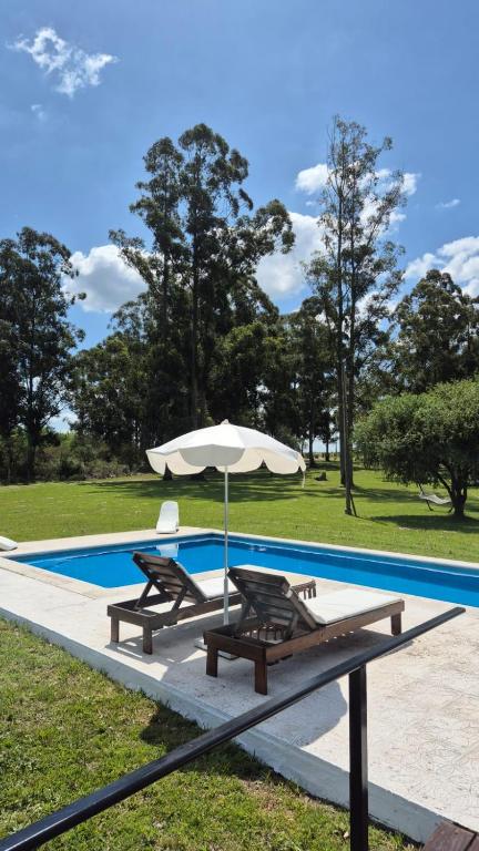 a pool with two chairs and an umbrella at Posada Los Molles in Colón