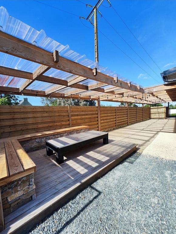 une terrasse en bois avec un banc sous une pergola en bois dans l'établissement La villa de Sofie, à Lantic