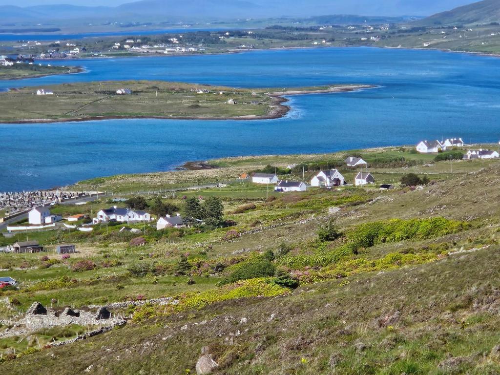 Achill Island Holiday home by the Sea - Idyllic views, Sleeps 6, Full kitchen, Fireplace and Wifi throughout في Achill Sound: صورة جوية لقرية ومسطح مائي