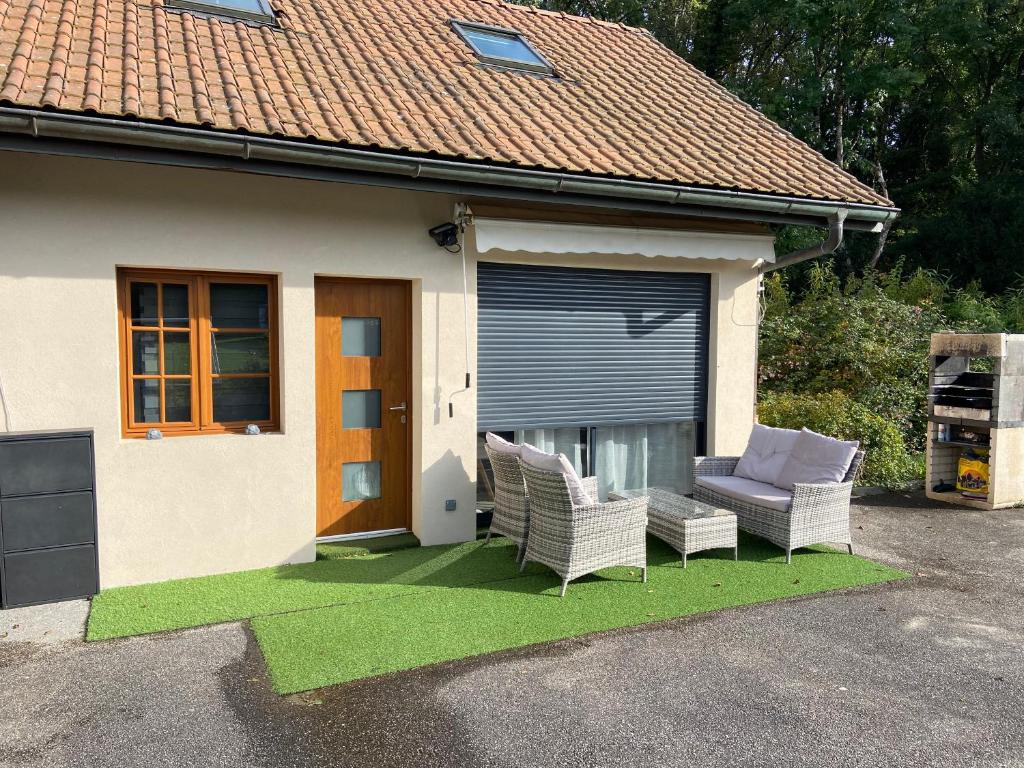 a house with two chairs and a couch on a patch of grass at Appartement aux portes de Genève in Archamps