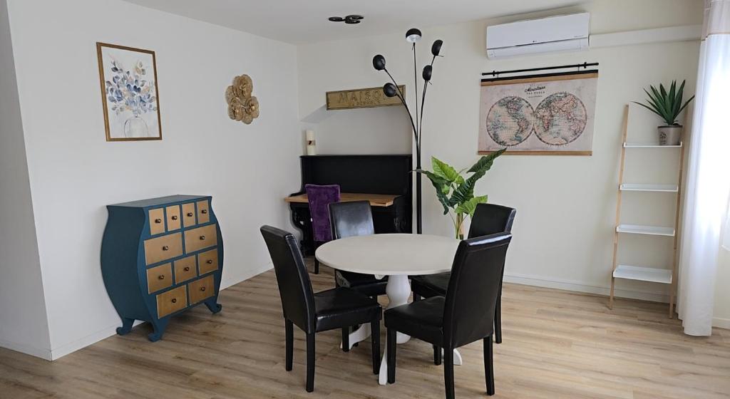 een eetkamer met een witte tafel en zwarte stoelen bij Landon Cottage in Campénéac