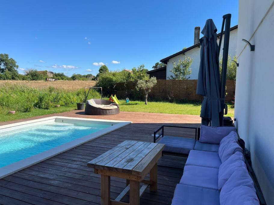 une terrasse avec un banc, un parasol et une piscine dans l'établissement La maison du bonheur entre Bordeaux et Océan, à Saint-Médard-en-Jalles