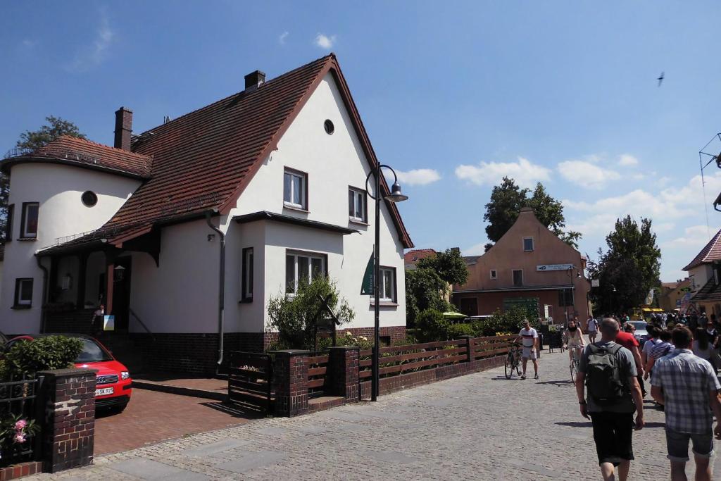 a group of people walking down a street next to a white house at Ferienwohnung am Hafen in Lübbenau