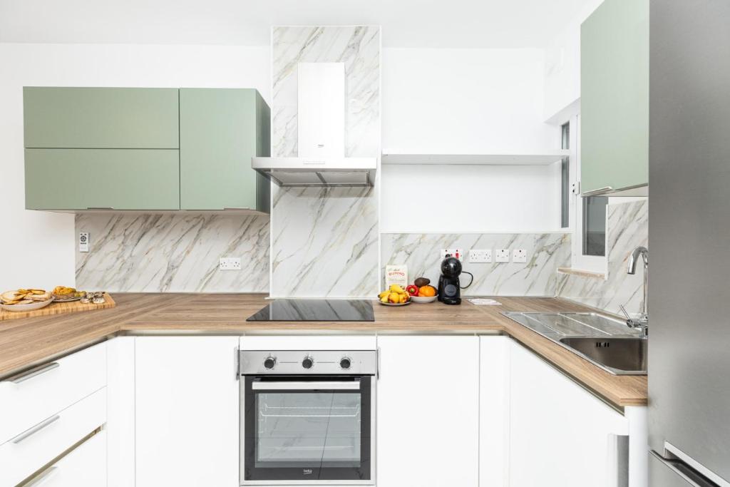 a white kitchen with white cabinets and a sink at kensington in St. Paul's Bay