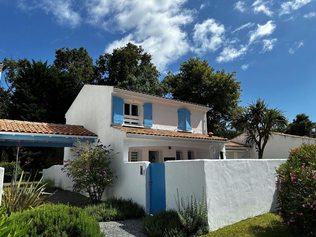 une maison blanche avec des fenêtres bleues et une clôture dans l'établissement La Maison du Bonheur 2 ch 65m2 - patio et jardin - Les Mathes - Locsweethome, aux Mathes