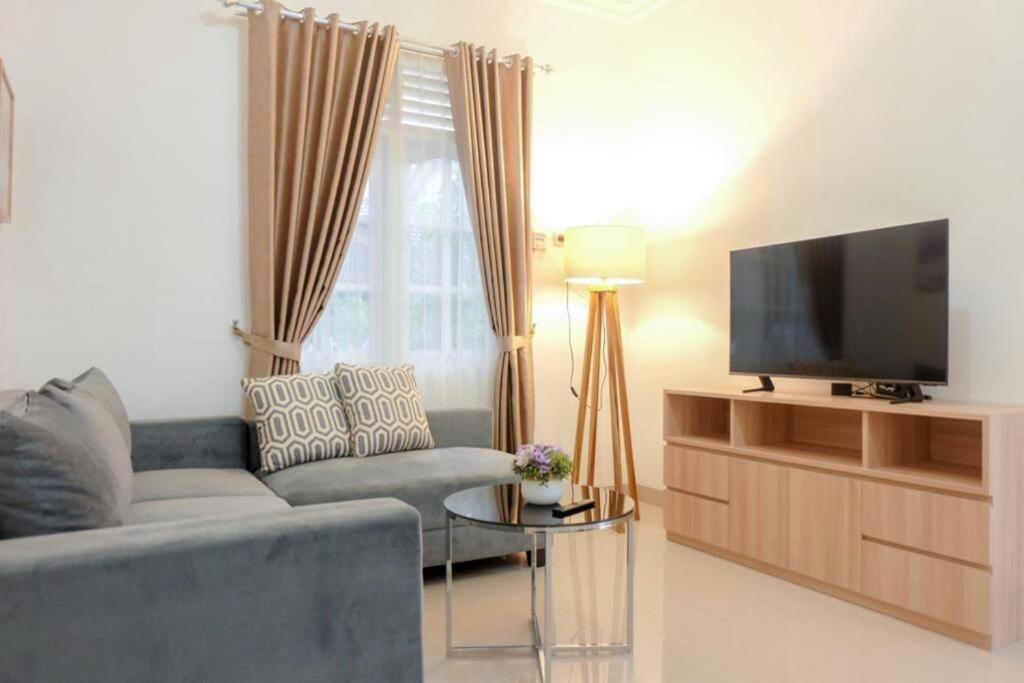 a living room with a couch and a flat screen tv at Kamiliya Homestay in Ngabean