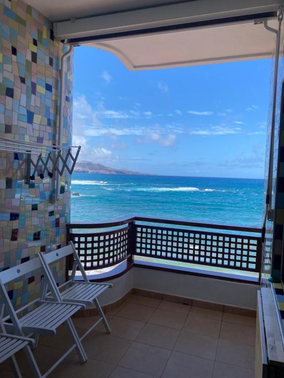a balcony with chairs and a view of the ocean at Estudio luminoso, primera línea de playa de las canteras in Las Palmas de Gran Canaria
