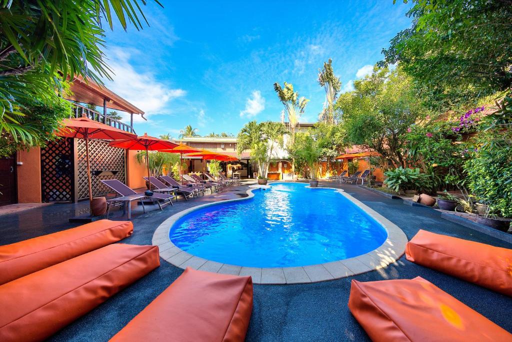 a swimming pool with orange pillows and chairs next to a house at Eden Bungalows Fisherman's village in Bophut 