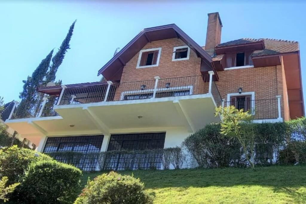 a house on a hill with bushes and trees at Casa e Vista privilegiadas no Alto do Capivari in Campos do Jordão