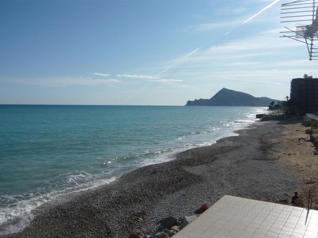 uma praia com o oceano e uma colina ao fundo em Hostal El Trovador em Altea