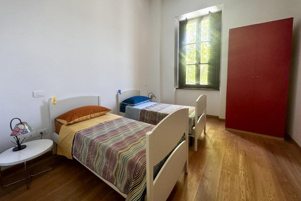 a bedroom with two beds and a table and a window at La CASA al CENTRO in LʼAquila