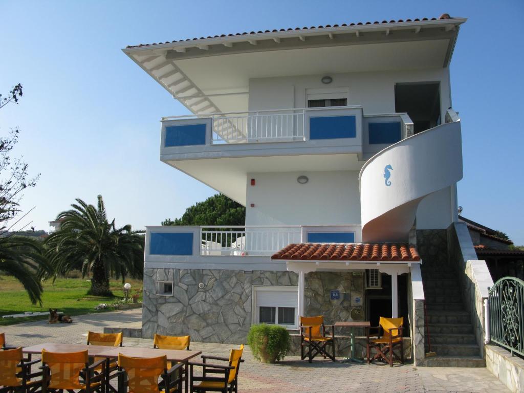 a building with tables and chairs in front of it at Seaview Aparthotel in Nea Potidaea