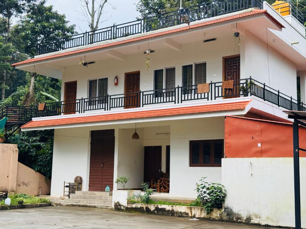 a house with a balcony on top of it at Dubare plantation stay in Siddapur