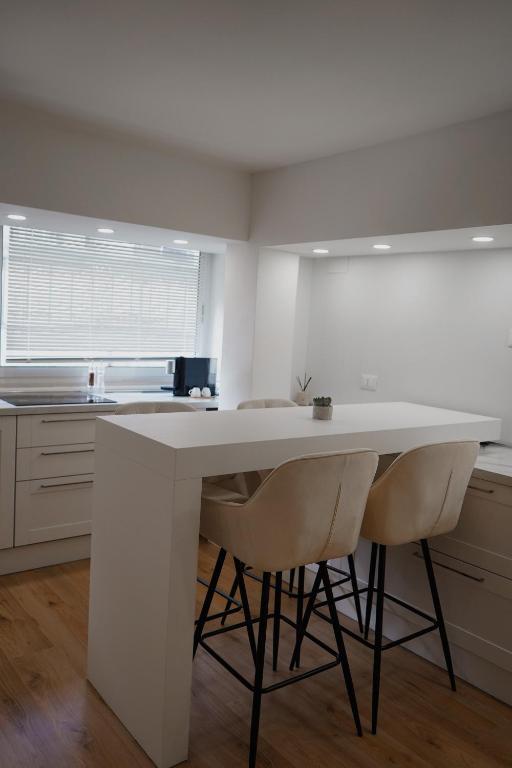 a kitchen with a large white counter and two chairs at La Perla Apartment in Taranto