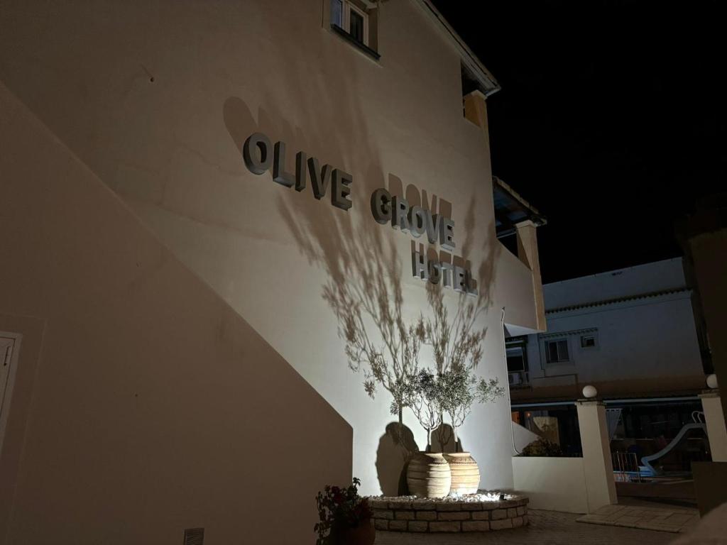 a sign on the side of a building with a plant at olivegrove in Sidari