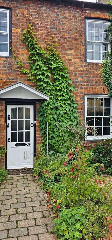 a brick building with a white door in front of it at Victorian Retro Cottage in Stony Stratford Centre in Stony Stratford