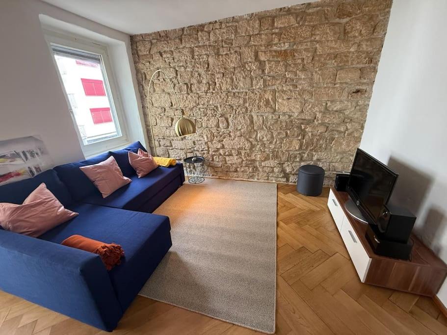 a living room with a blue couch and a brick wall at Artsy und Cosy nahe Norvatis Campus in Basel St Johann in Basel