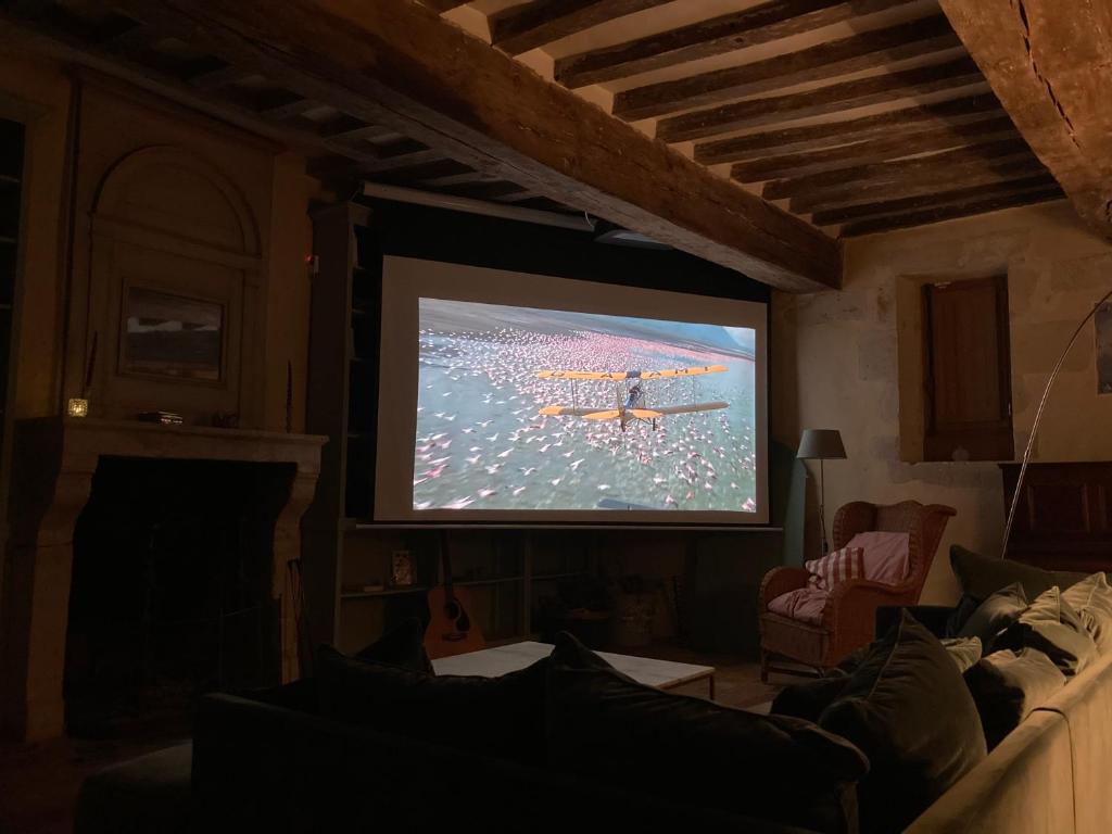 a living room with a tv with a person on the screen at La Breteche du Perche in Saint-Germain-de-la-Coudre