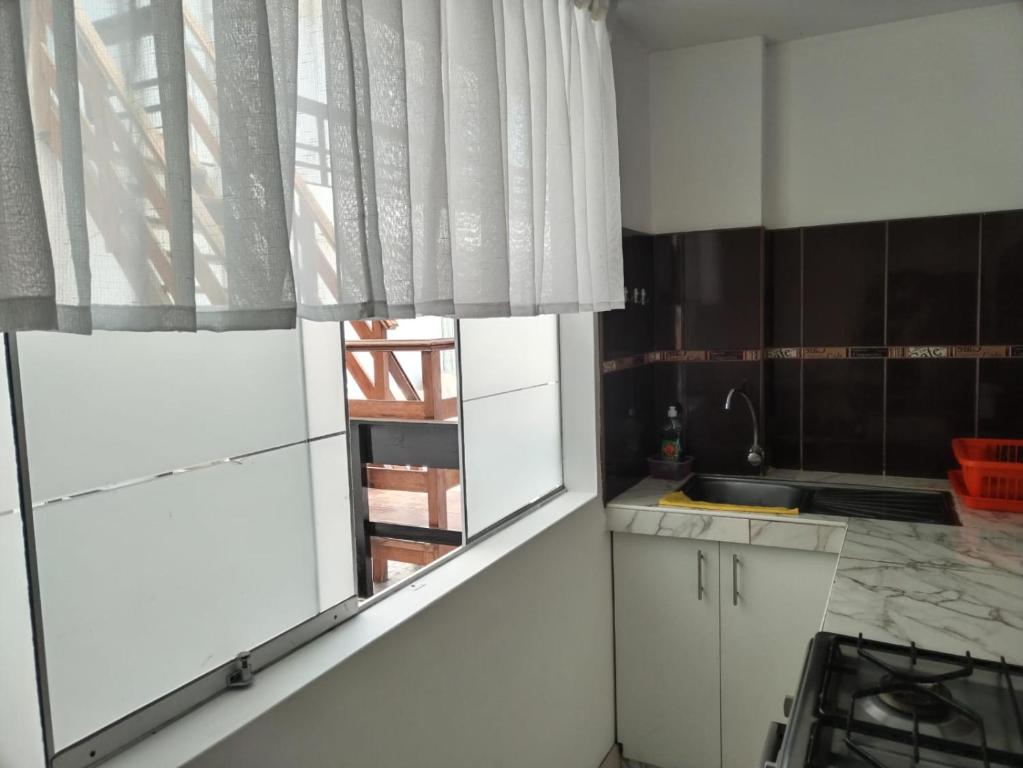 eine Küche mit weißen Schränken, einem Fenster und einem Waschbecken in der Unterkunft Departamento Acogedor Céntrico en Huanchaco3B in Huanchaco
