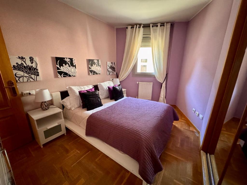 a bedroom with a bed with purple walls and a window at Apartamento Marqués parking gratuito in Oviedo