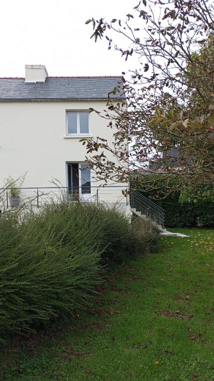 une maison blanche avec une clôture et un peu d'herbe dans l'établissement Petite maison avec jardin, à Landrévarzec