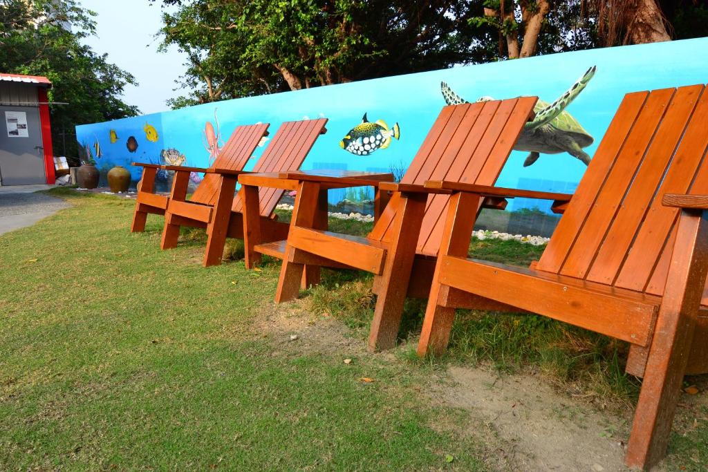 a row of wooden benches in front of a wall at Haichian Hostel in Xiaoliuqiu