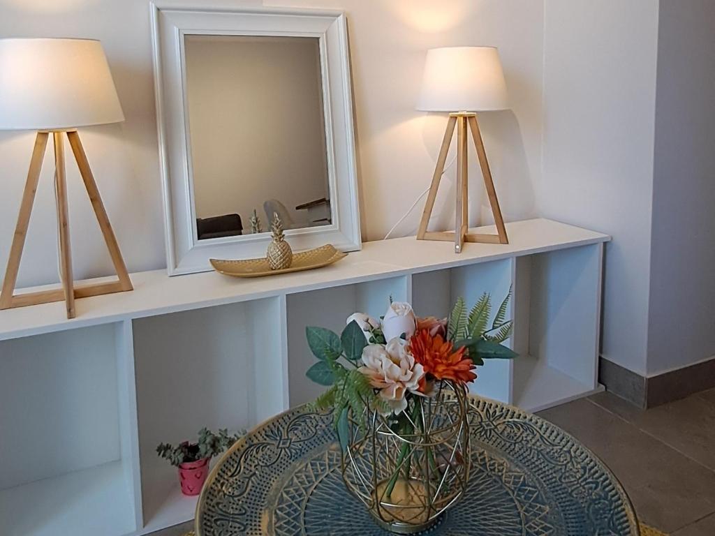 a vase with flowers on a table with two lamps at Montenegro 2 dormitorios in Temuco