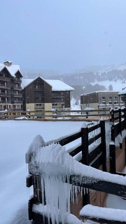 une clôture recouverte de neige avec des bâtiments en arrière-plan dans l'établissement Chez Simon, à Risoul