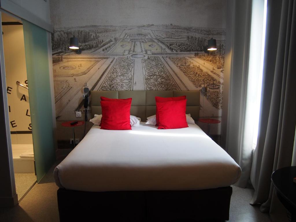 duże łóżko z czerwonymi poduszkami w pokoju w obiekcie Porte de Versailles Hotel w Paryżu