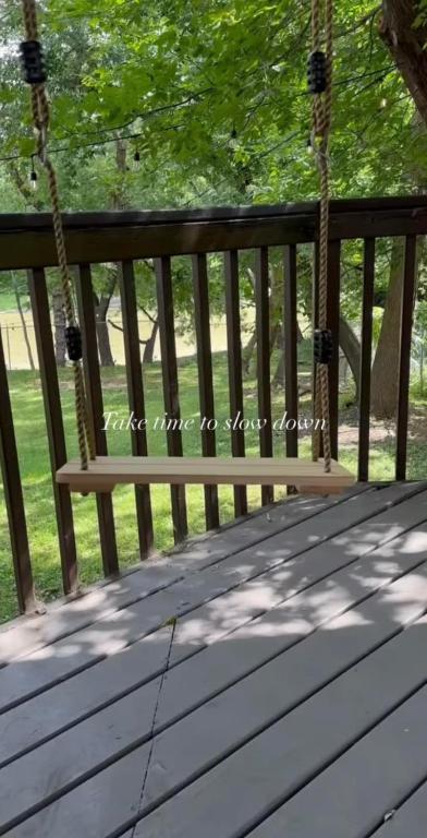 a wooden swing on a porch with a tree at No. 5 East in Winnipeg