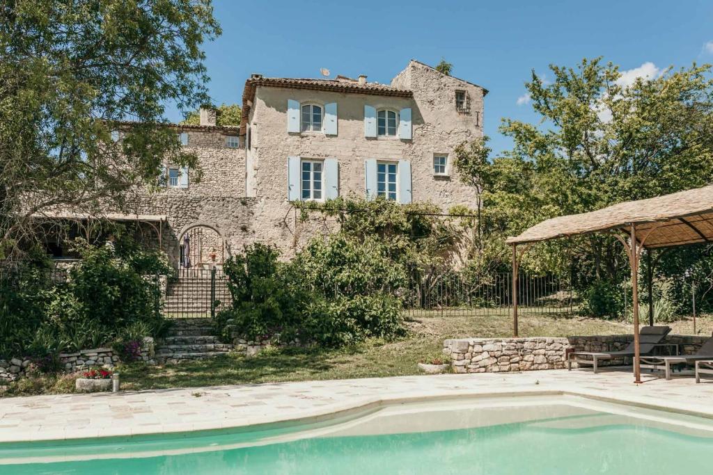 une ancienne maison en pierre avec une piscine en face de celle-ci dans l'établissement Le Bas Château Provence Luberon, à Saint-Michel-lʼObservatoire