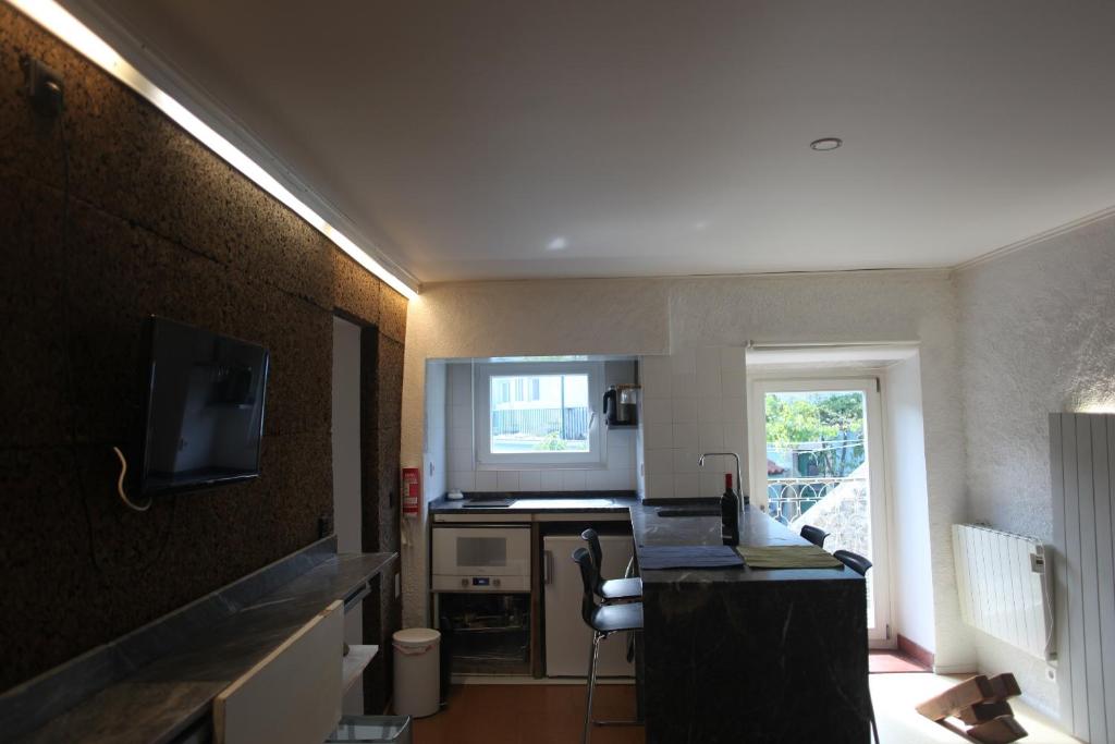 a room with a kitchen with a counter and a television at ribeira dos marinheiros amarelo in Sintra