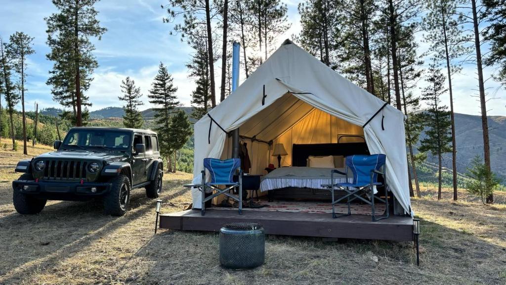 a tent with a bed and two chairs and a jeep at Tent 2 Oxen-Le-Fields Montana in Conner