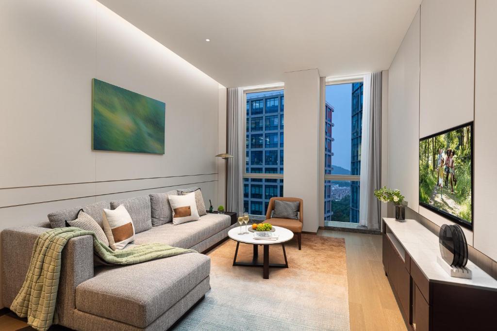 a living room with a couch and a tv at Somerset QPlex Shenzhen in Shenzhen