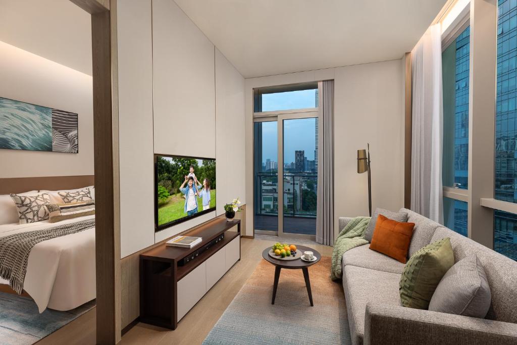 a living room with a couch and a tv at Somerset QPlex Shenzhen in Shenzhen