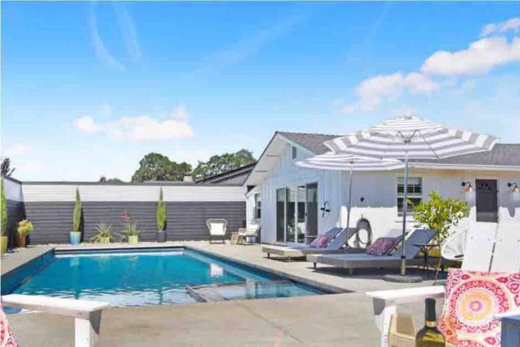 a swimming pool with an umbrella next to a house at Relaxing Palmer Farmhouse Pool Hot Tub Putting in Sonoma