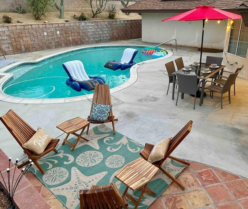 a pool with chairs and a table and an umbrella at 4 Bedroom King Beds One-Story Tesla EV in Riverside
