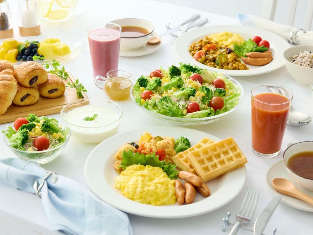 a table with plates of breakfast foods and drinks at Comfort Hotel Tokyo Kanda in Tokyo