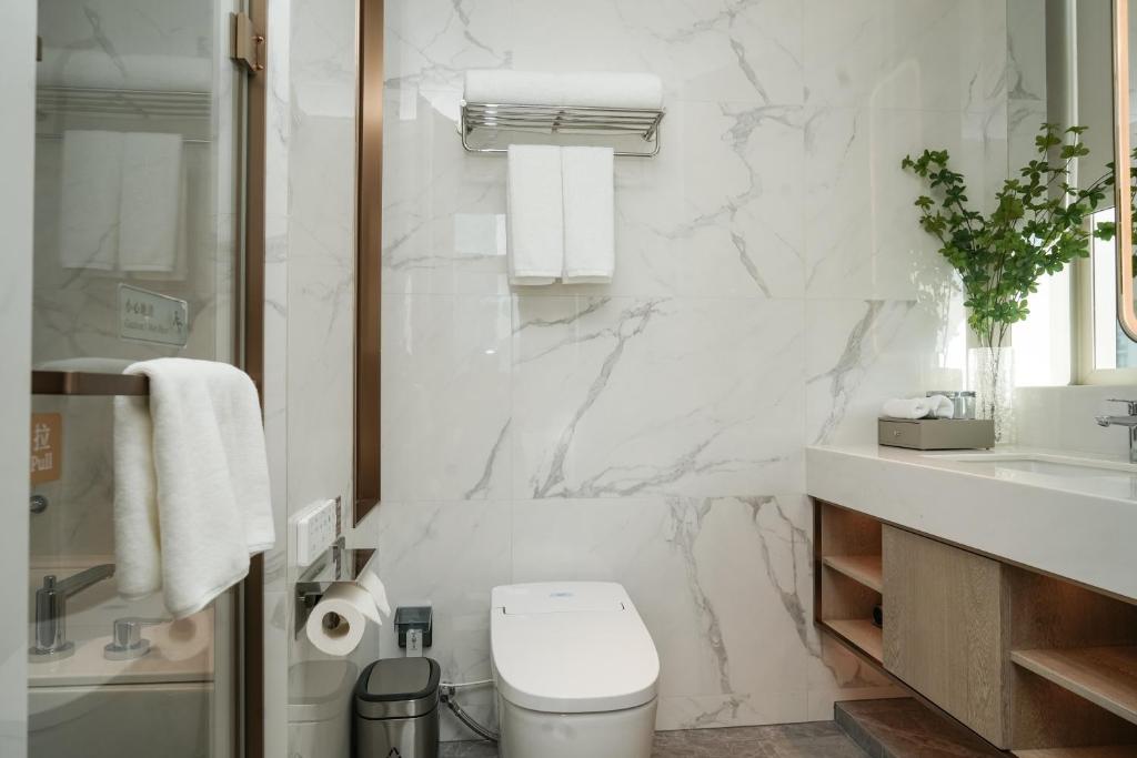 a white bathroom with a toilet and a sink at Somerset QPlex Shenzhen in Shenzhen